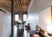 Thumbnail 42 of 99 - A room with a wooden ceiling and a white wall with a lamp on a table.at Plant 1 Lofts, N. Newton  