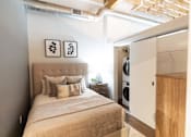 Thumbnail 43 of 99 - A bedroom with a bed, pillows, and a wooden cabinet.at Plant 1 Lofts, Iowa   