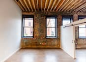 Thumbnail 59 of 99 - A room with a white door and windows with a brick wall.at Plant 1 Lofts, N. Newton Iowa   