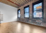 Thumbnail 57 of 99 - A room with wooden floors and a white wall with a window.at Plant 1 Lofts, Iowa   