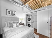 Thumbnail 48 of 99 - A bedroom with a bed, pillows, and a white wall with two framed pictures.at Plant 1 Lofts, N. Newton  