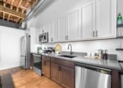 Thumbnail 49 of 99 - A kitchen with a stainless steel dishwasher and a refrigerator.at Plant 1 Lofts, N. Newton Iowa   