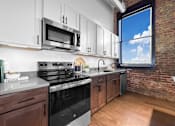 Thumbnail 50 of 99 - A kitchen with a black stove top oven and a microwave above it.at Plant 1 Lofts, N. Newton, 50208  