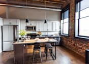 Thumbnail 26 of 99 - A kitchen with a table and chairs in front of a brick wall.at Plant 1 Lofts, N. Newton, 50208  