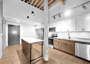Thumbnail 63 of 99 - A kitchen with a white table and wooden cabinets.at Plant 1 Lofts, N. Newton, IA  