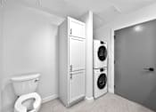Thumbnail 67 of 99 - A white toilet sits next to a white cabinet and a washing machine in a laundry room.at Plant 1 Lofts, N. Newton, IA 50208  