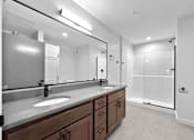 Thumbnail 69 of 99 - A bathroom with a sink, mirror, and a walk-in shower.at Plant 1 Lofts, Iowa   