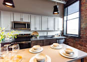 Thumbnail 27 of 99 - A kitchen with a table set for two with plates and glasses.at Plant 1 Lofts, Iowa   