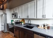 Thumbnail 28 of 99 - A kitchen with white cabinets and a black sink.at Plant 1 Lofts, N. Newton, IA  