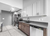 Thumbnail 84 of 99 - A modern kitchen with white cabinets and stainless steel appliances.at Plant 1 Lofts, Iowa   