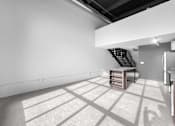 Thumbnail 94 of 99 - A room with a white wall and a wooden staircase.at Plant 1 Lofts, N. Newton, IA 50208  