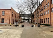 Thumbnail 95 of 99 - A long brick building with a walkway in front.at Plant 1 Lofts, N. Newton, IA  