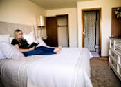 Thumbnail 3 of 57 - a woman sitting on a bed reading a book  at Bristol Ridge, Urbandale, IA, 50322
