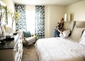 Thumbnail 5 of 57 - a woman piling pillows on a bed in a master bedroom at Bristol Ridge, Iowa, 50322