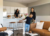Thumbnail 15 of 57 - a young boy playing in a living room with his parents at Rialto Townhomes Apartments, Iowa