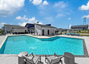 Thumbnail 46 of 57 - a swimming pool with chairs and a building in the background at Rialto Townhomes Apartments, Waukee