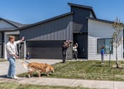 Thumbnail 55 of 57 - a man walking his dog in front of a house at Rialto Townhomes Apartments, Waukee, IA