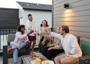 Thumbnail 36 of 57 - a group of people sitting on a patio with drinks at Rialto Townhomes Apartments, Iowa, 50263