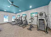 Thumbnail 50 of 57 - a gym with cardio machines and a ceiling fan at Rialto Townhomes Apartments, Iowa