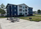 Thumbnail 7 of 7 - A large apartment complex with a picnic table in front.