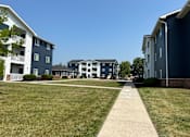 Thumbnail 2 of 7 - A grassy area in front of apartment buildings.