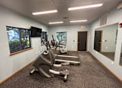 Thumbnail 6 of 7 - A gym room with a treadmill and exercise bike.