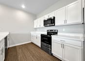 Thumbnail 27 of 51 - A kitchen with white cabinets and a black microwave.