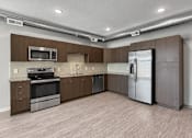 Thumbnail 4 of 59 - A kitchen with a refrigerator, oven, and microwave.