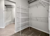Thumbnail 6 of 59 - Empty walk-in closet with shelves and a doorway leading to another room.