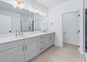 Thumbnail 60 of 77 - Bathroom vanity with dual sinks and gold fixtures at The Flats at West Glen Apartments, West Des Moines, Iowa