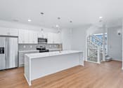 Thumbnail 54 of 77 - Modern kitchen with island and staircase at The Flats at West Glen Apartments, West Des Moines, IA