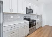 Thumbnail 53 of 77 - Modern kitchen with white cabinets and stainless appliances at The Flats at West Glen Apartments, West Des Moines, Iowa