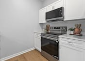 Thumbnail 47 of 53 - A kitchen with white cabinets and a black microwave.