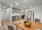 Thumbnail 3 of 53 - A modern kitchen with a dining table set with a bowl of fruit.
