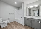 Thumbnail 8 of 53 - A white toilet sits in a bathroom with a wooden floor and white walls.