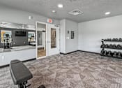 Thumbnail 35 of 53 - A gym room with a bench, weights, and a mirror.