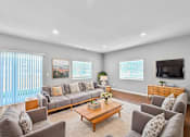 Thumbnail 6 of 51 - A living room with a grey couch, a coffee table, and a television.