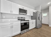 Thumbnail 9 of 51 - A kitchen with white cabinets and stainless steel appliances.