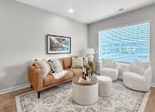 Thumbnail 3 of 90 - A living room with a brown couch, two white armchairs, and a coffee table.
