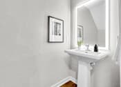 Thumbnail 72 of 90 - A white sink under a mirror with a picture frame hanging on the wall.