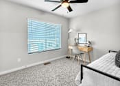 Thumbnail 70 of 90 - A room with a bed, desk, chair, and window with blinds.