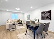 Thumbnail 12 of 36 - A modern, finished basement with a sectional, sitting area, extra bathroom, and wet bar.