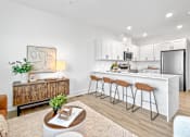 Thumbnail 15 of 36 - A brand new, modern townhome kitchen with white cabinets and a bar area with stools.