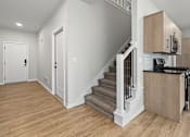 Thumbnail 15 of 34 - A white interior with a staircase and a kitchen area.
