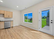 Thumbnail 11 of 34 - A kitchen with wooden floors and a window showing a green lawn outside.