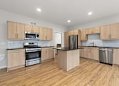 Thumbnail 2 of 34 - A kitchen with wooden cabinets and a black refrigerator.