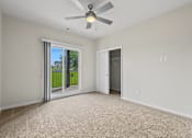 Thumbnail 18 of 34 - A room with a ceiling fan and carpeted floor.