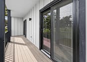Thumbnail 14 of 34 - A long balcony with a black railing and a glass door.