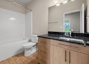 Thumbnail 17 of 34 - A white toilet sits in a bathroom with wooden cabinets.