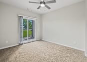 Thumbnail 13 of 34 - A room with a ceiling fan and carpeted floor.